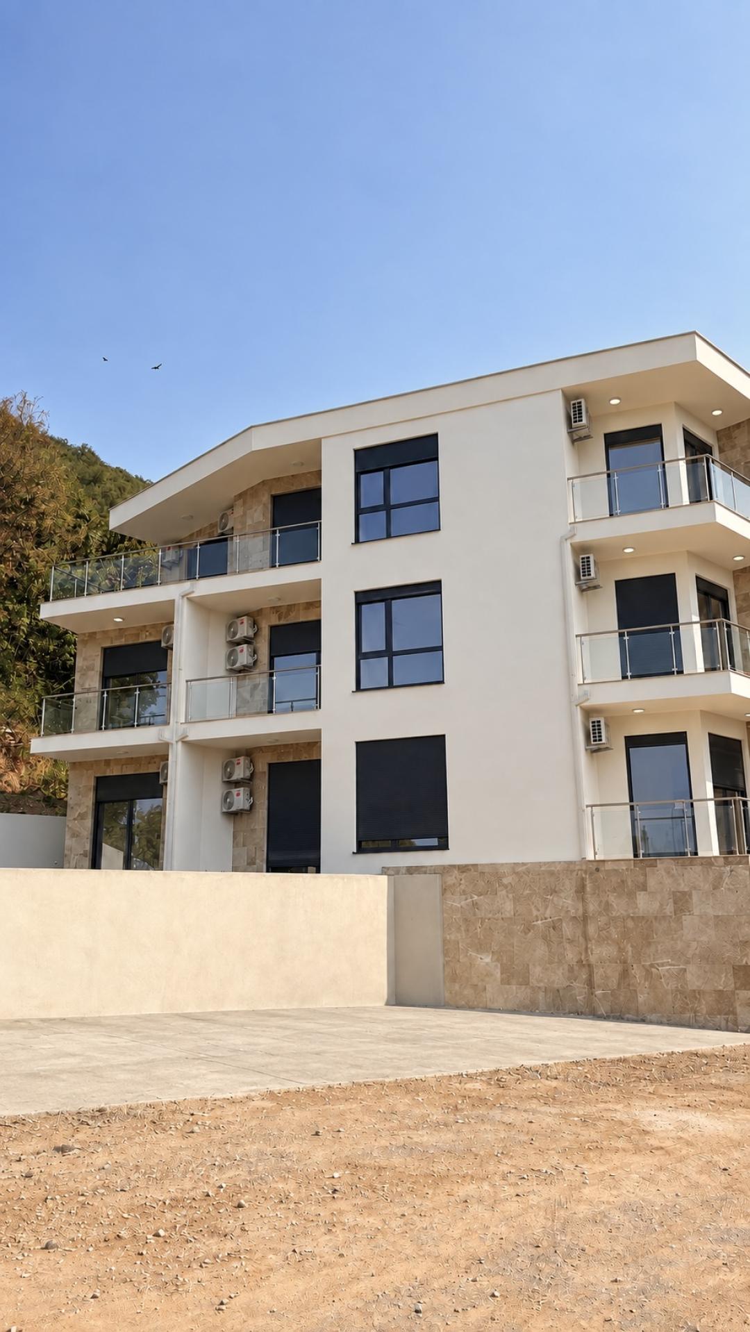 <p>The project is an exclusive residential complex located in one of the most picturesque areas of Tivat. Modern architecture, high-quality materials, and well-thought-out layouts create the perfect space for comfortable living.</p><p><br>Advantages of the Complex:</p><p><br>Prime Location: Just a few minutes’ walk from the beaches, restaurants, and the Porto Montenegro waterfront.</p><p><br>High-End Finishes: Natural stone, premium sanitary ware, and climate systems from leading global brands.</p><p><br>Functional Layouts: Maximum use of space and natural light thanks to panoramic windows.</p><p><br>Professional Management: The complex will be maintained by an experienced property management company.</p><p><br>Location</p><p><br>The residential complex is situated in a quiet and green area of Tivat, surrounded by scenic nature and prestigious developments.<br>Shops, restaurants, clean beaches, and the world-renowned Porto Montenegro marina — one of the most elite ports in Europe — are all within walking distance.<br>Tivat International Airport is just a 10-minute drive away, ensuring maximum travel convenience.<br>By choosing Tivat as your new home, you become part of a dynamically developing resort with modern infrastructure — where every day is filled with comfort and new experiences.<br><br>About the Complex<br>The complex consists of two buildings — Block A and Block B.<br>Each block offers one- and two-bedroom apartments with spacious living rooms and terraces.<br>Ground floor units feature private patios.<br>Available apartments range from 42 m² to 90 m².<br>Thanks to panoramic glazing, all apartments are filled with natural light throughout the day. Most units offer breathtaking views of the sea and the city.<br>&nbsp;</p>